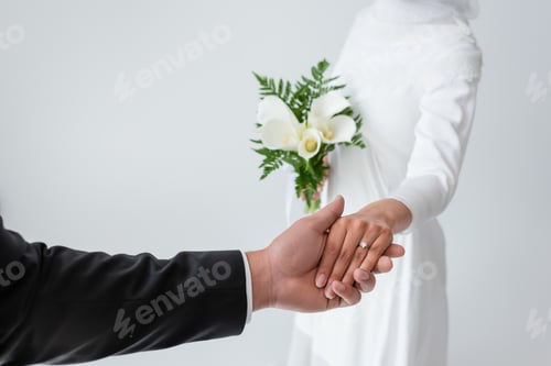 Preview: Cropped View of Bride With Bouquet Holding Hands With Blurred Groom Isolated on Grey