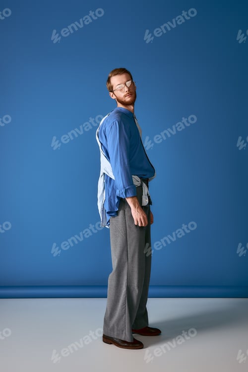 Preview: Handsome man with red hair showcases stylish attire against a bold blue background