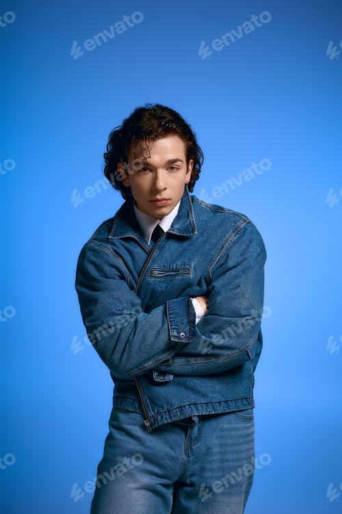 Preview: Handsome young man with curly hair showcases fashion style in vibrant blue background