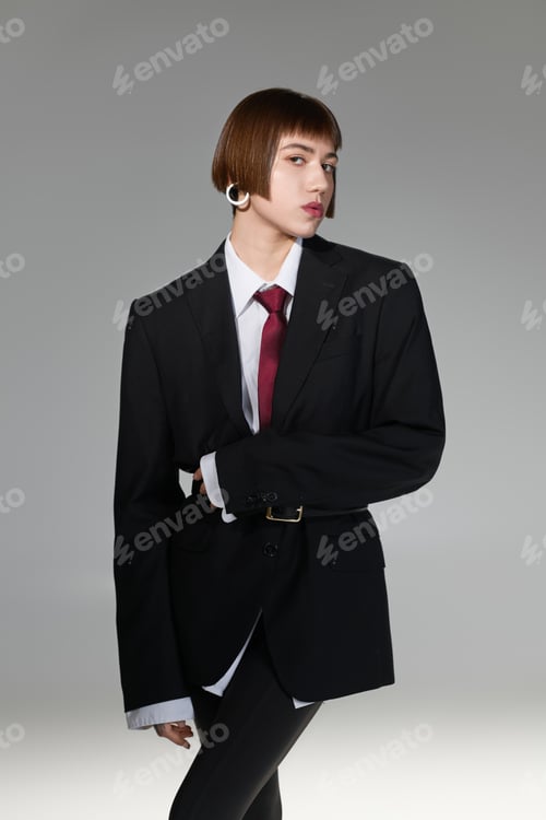 Preview: Stylish young woman in oversized suit jacket showcasing modern fashion trends in an artistic setting