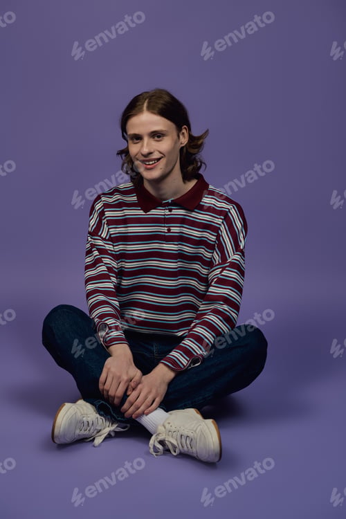 Preview: Young man showcases stylish outfit in modern studio with vibrant purple backdrop