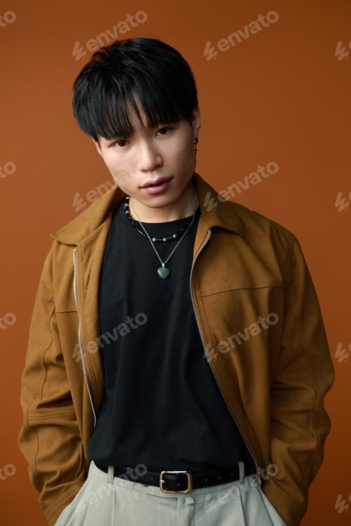 Preview: Young handsome man with captivating gaze poses confidently in a stylish outfit and warm background