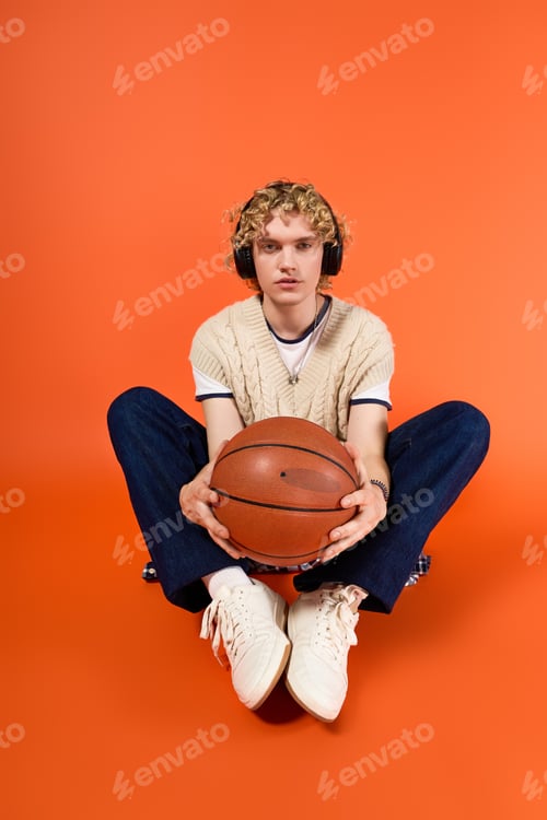 Preview: Young man expressing trendy style with basketball in vibrant studio setting