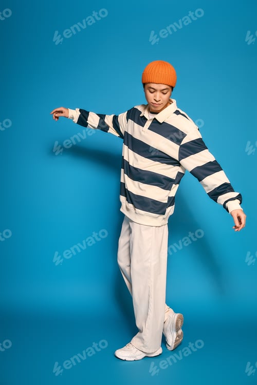 Preview: Stylish young man showcasing modern fashion in a vibrant blue studio setting
