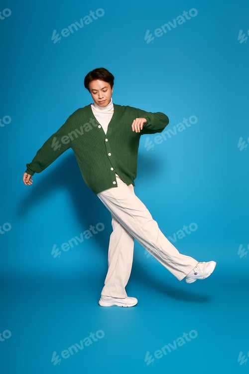 Preview: Stylish young man expresses unique fashion sense in vibrant studio setting