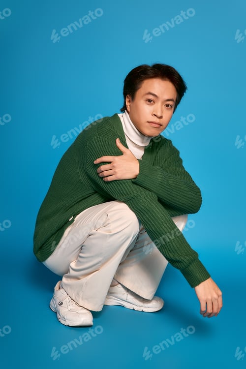 Preview: Stylish young man showcases modern fashion in vibrant studio setting