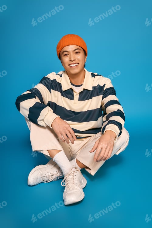 Preview: Stylish asian young man expressing unique fashion sense in vibrant studio setting