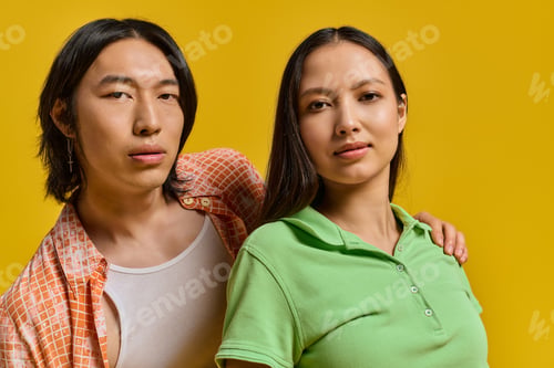 Preview: Stylish young couple exudes love and joy against a vibrant yellow backdrop