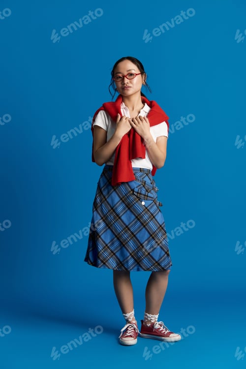 Preview: Young Asian woman models a stylish outfit against a vibrant blue urban backdrop