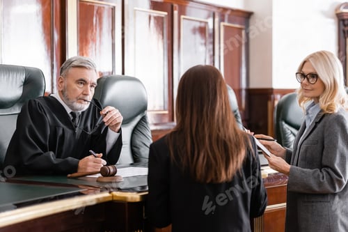 Preview: Thoughtful Judge Holding Eyeglasses Listen to Prosecutor Standing Near Attorney in Court