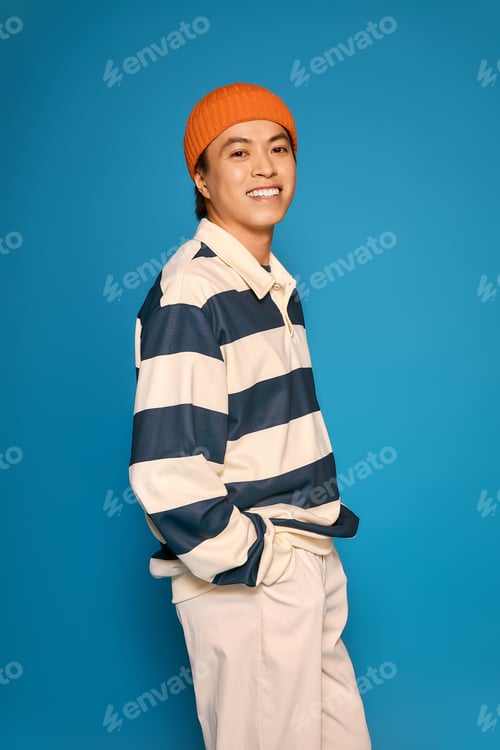 Preview: Stylish young man showcases vibrant fashion sense in a bold studio setting