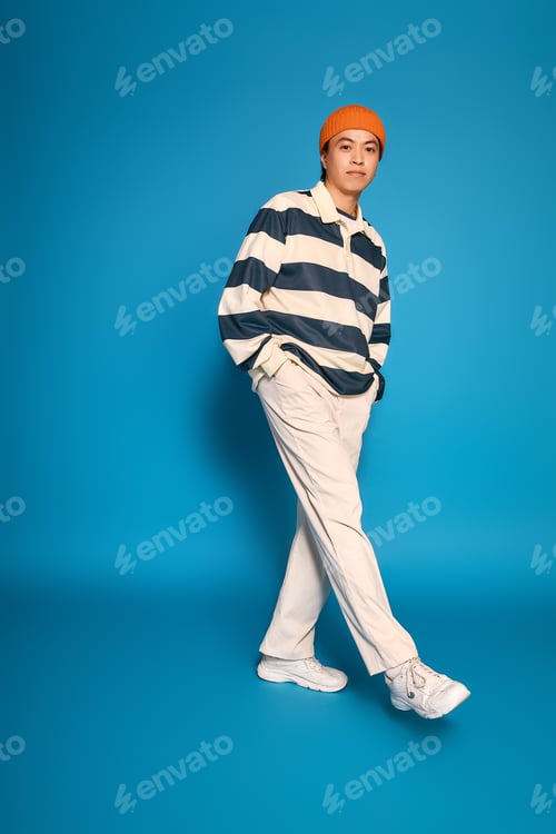 Preview: Stylish young asian man showcasing fashion in vibrant studio setting