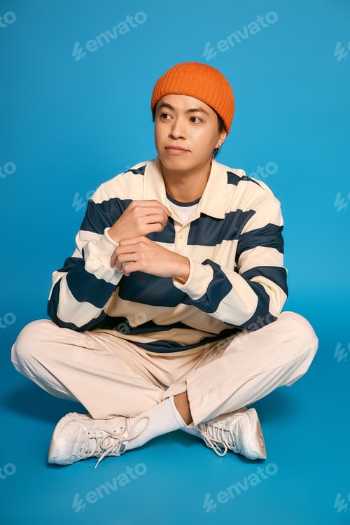 Preview: Stylish young man in a striped outfit showcases modern fashion in a bright studio setting
