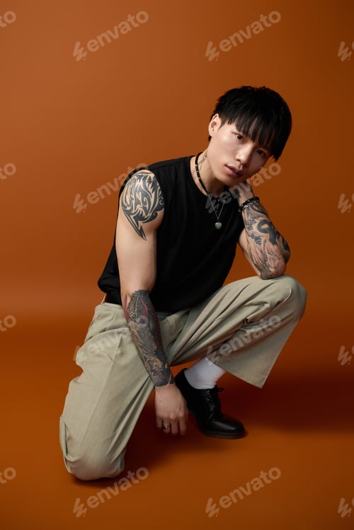 Preview: Stylish young man poses confidently against a rich, warm backdrop in a creative studio setting