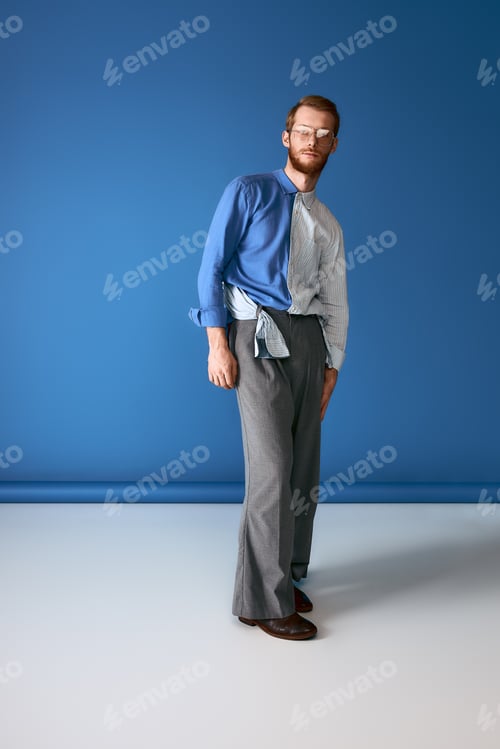 Preview: Confident red haired man showing modern fashion with bold style against a vibrant blue backdrop