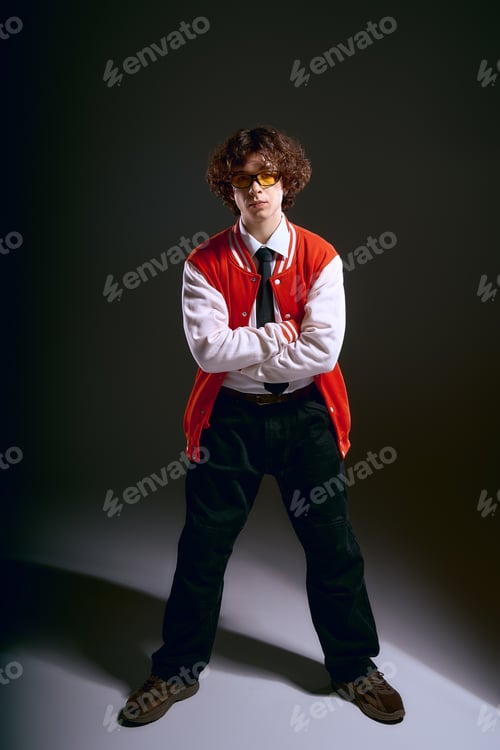 Preview: Young man exudes confidence in trendy outfit with a moody backdrop in contemporary style