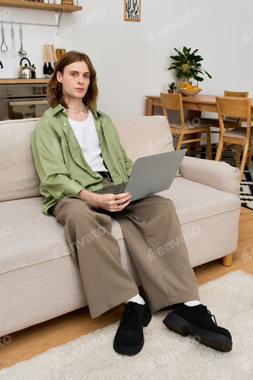 Preview: Young androgynous man enjoying a cozy moment at home in a modern apartment