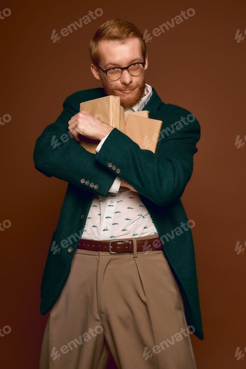 Preview: Stylish red haired man embraces books with charm in an elegant indoor setting
