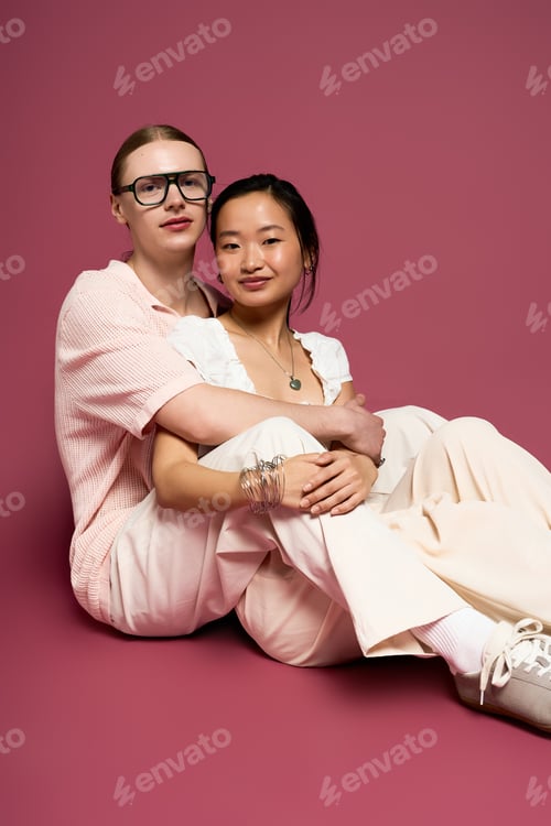 Preview: Young couple sharing warmth and affection in a cozy setting against a pink backdrop