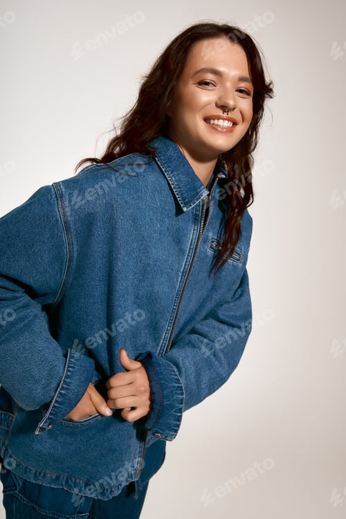 Preview: Stylish young woman radiates confidence in trendy denim jacket against neutral backdrop