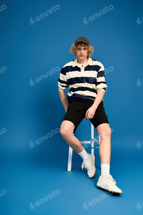 Preview: Curly blonde young man showcasing casual fashion in a bright studio setting