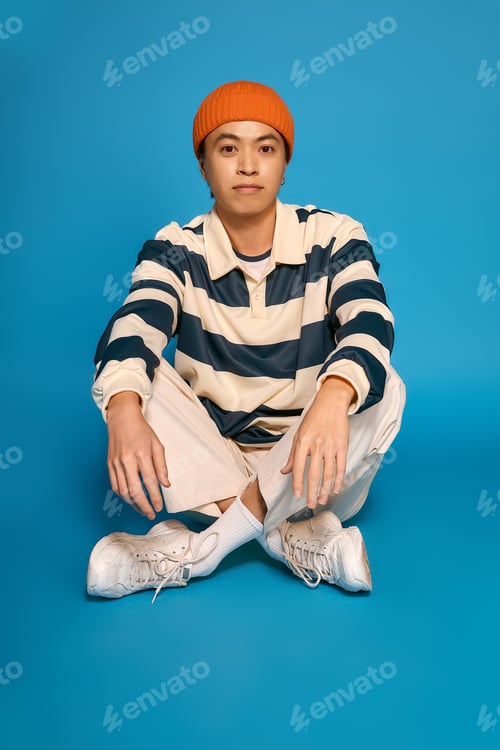 Preview: Stylish young man showcases his unique outfit in dynamic studio setting