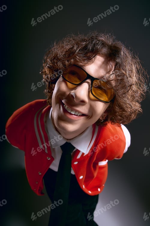 Preview: Joyful young man with curly hair and stylish glasses in a trendy, artistic setting