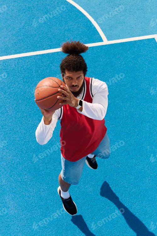 Preview: Young man shoots basketball in vibrant outdoor court on sunny day