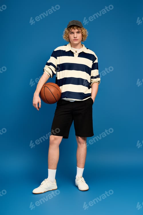 Preview: Stylish young man with curly blonde hair showcasing trendy casual attire in a studio