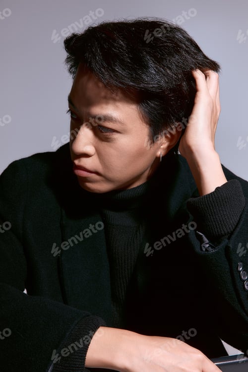 Preview: Stylish asian young man presents unique fashion in a modern studio setting