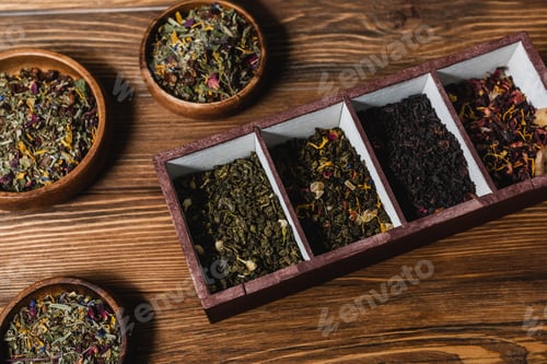 Preview: Top view of dry tea in box and bowls on wooden surface