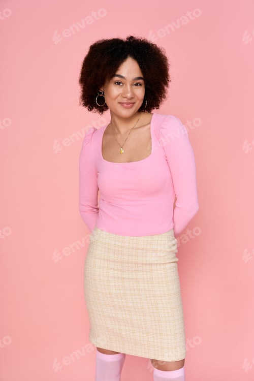 Preview: Fashionable young woman poses gracefully against a soft pink backdrop while exuding confidence