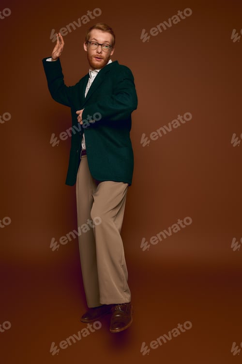 Preview: Handsome red haired man showcasing stylish fashion in a brown studio backdrop