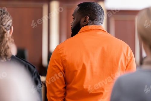 Preview: Back View of African American Man in Jail Uniform Near Guard and Blurred Jurors in Court