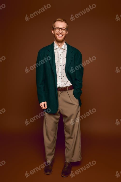 Preview: Handsome red haired man showcases stylish attire in a warm brown setting