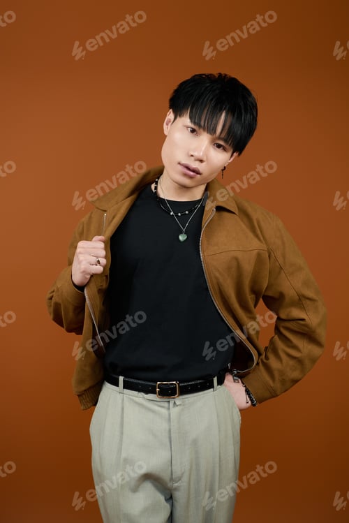 Preview: Stylish young man showcasing confidence against a warm, earthy backdrop