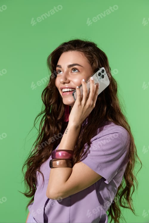 Preview: A beautiful woman with long hair smiles while chatting on her phone in a bright green setting