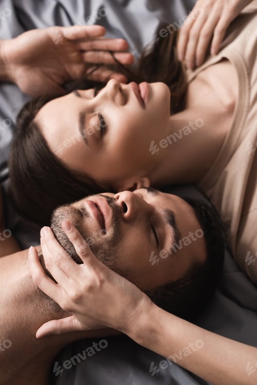 Preview: High angle view of pretty woman touching neck of boyfriend on bed