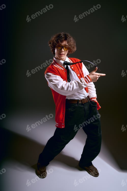Preview: Young man showcasing bold fashion with emotion in stylish outfit against dramatic lighting