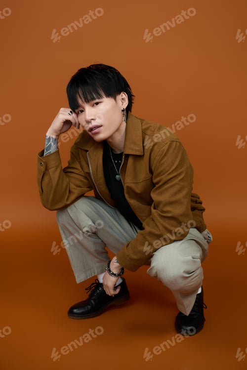 Preview: Stylish young man posing confidently against a warm, earthy background for a fashion look