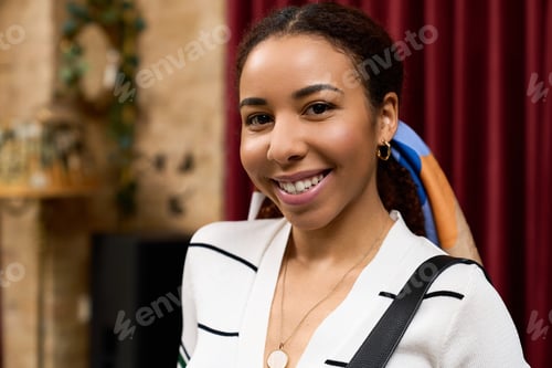 Preview: Young woman enjoys vibrant cafe atmosphere with casual style and joyful smile
