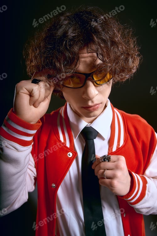 Preview: Young man with curly hair showcases unique style and emotion in vibrant red attire