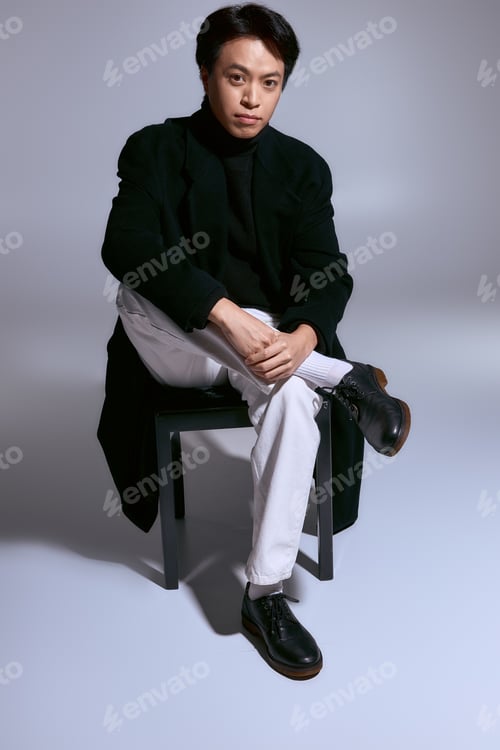 Preview: Stylish young man showcasing modern fashion in a minimalist studio setting