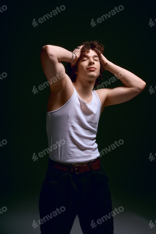 Preview: Emotional young man with curly hair showcases stylish attire in a moody setting