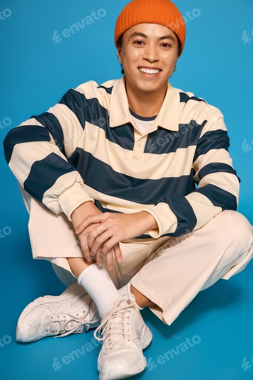 Preview: Stylish young man showcases vibrant outfit in lively studio setting