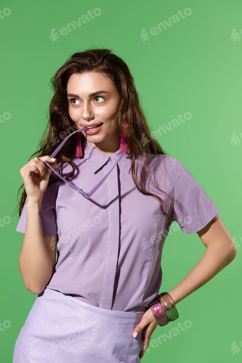 Preview: Stylish young woman showcasing vibrant fashion against a vivid green background