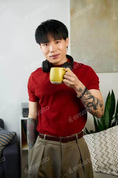 Preview: Young man enjoying a warm drink in a cozy living room filled with natural light