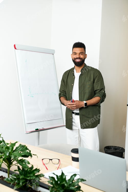 Preview: Young handsome man proudly presenting ideas at a bright office during an engaging meeting