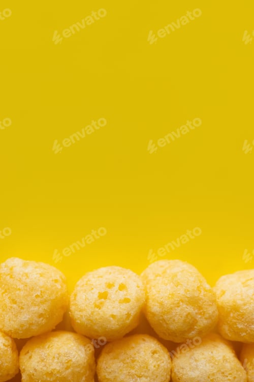 Preview: Top View of Puffed and Tasty Cheese Pops on Yellow