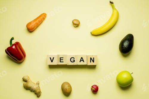 Preview: Top view of cubes with vegan lettering near fresh food on yellow background